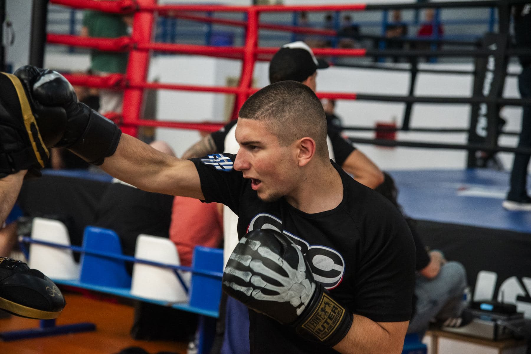 Αθλητής του Onomastos Boxing Club εκπνέει καθώς εκτείνει το χέρι του στους στόχους δίπλα στο ρινγκ.