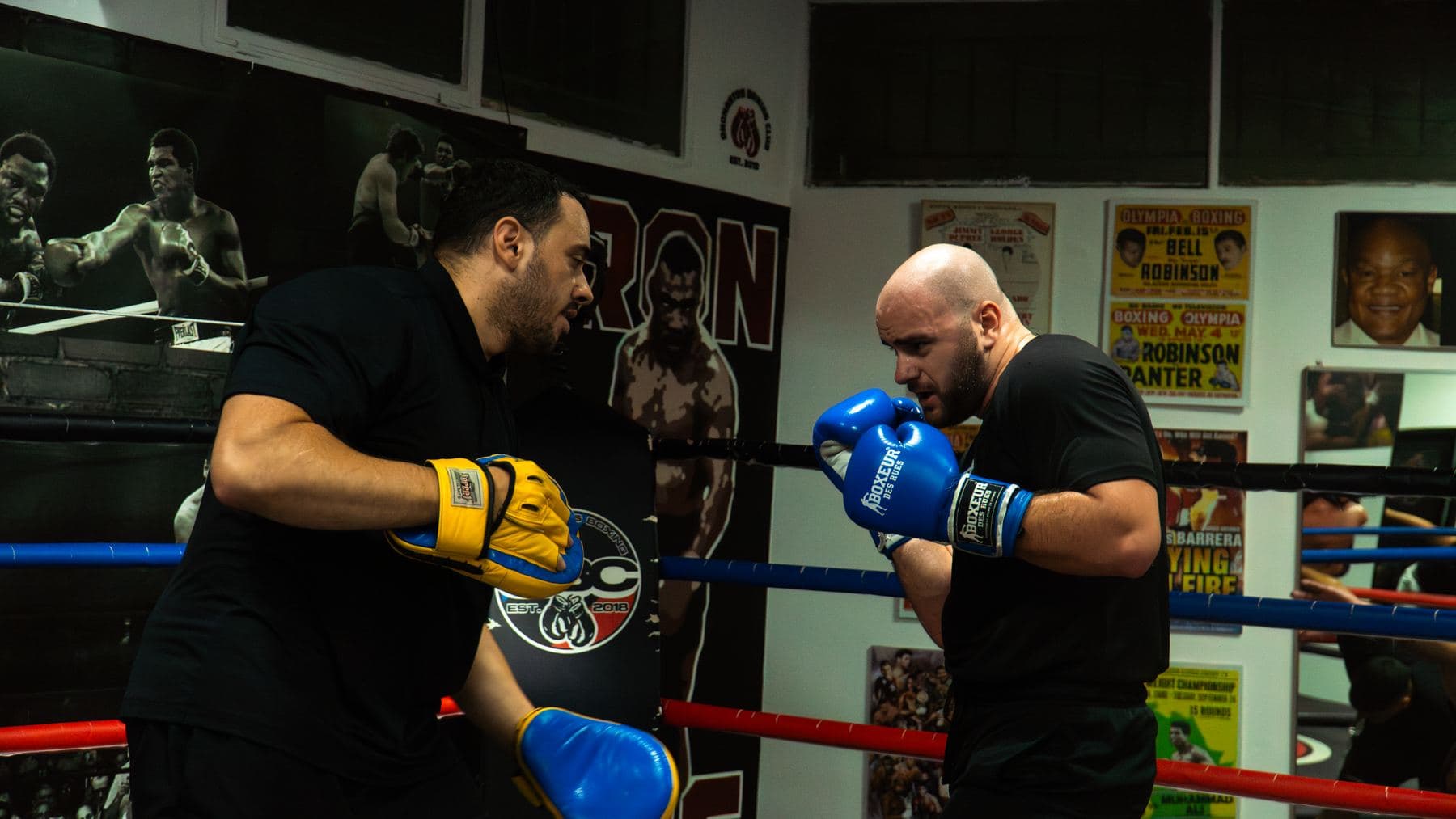 Προπονητής του Onomastos Boxing Club κρατά τους στόχους μέσα στο ρινγκ και καθοδηγεί τον αθλητή απέναντί του.